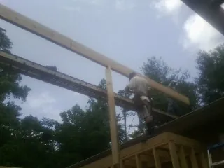 Carpenter setting a ridge beam over a new addition frame — Ice Dam Removal by Roofing Brothers in Austinville