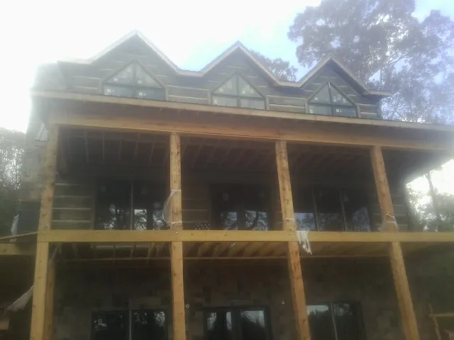 Dormers and porch framing on a large log home under construction — Roof Coating work by our crew in Austinville