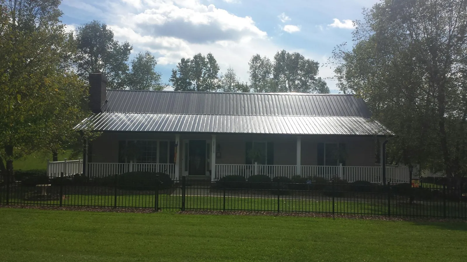 Gray metal roof on a brick ranch with a full width front porch — Gutter Guard Installation work by our crew in Austinville
