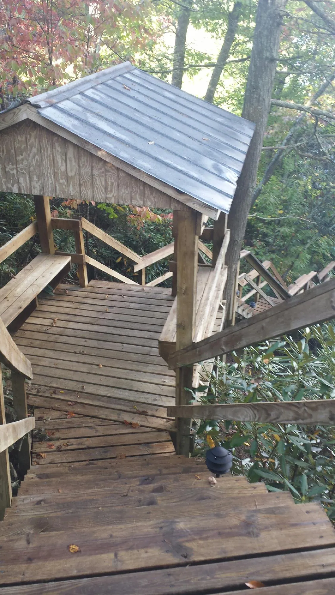 Metal roofed shelter over wooden steps on a wooded walkway — Skylight Repair & Installation work by our crew in Austinville