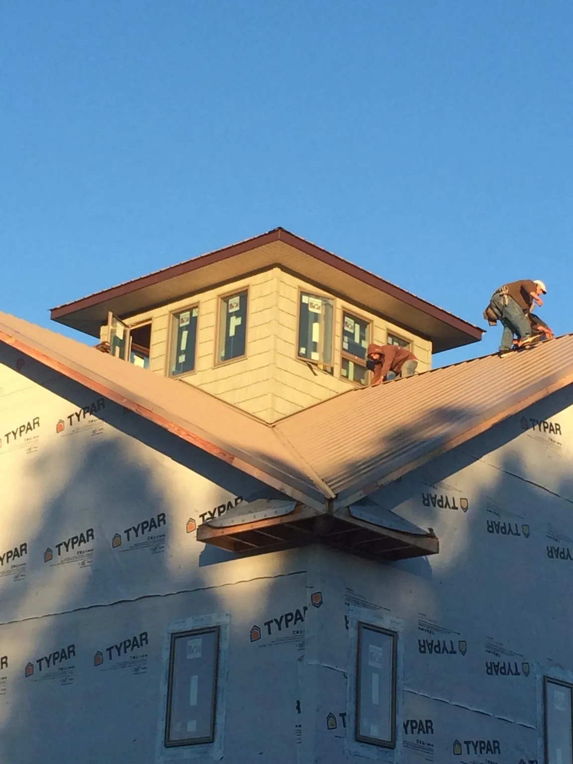 Roofers working around a rooftop cupola on a new metal roof at sunset — Roof Waterproofing in Austinville by Roofing Brothers